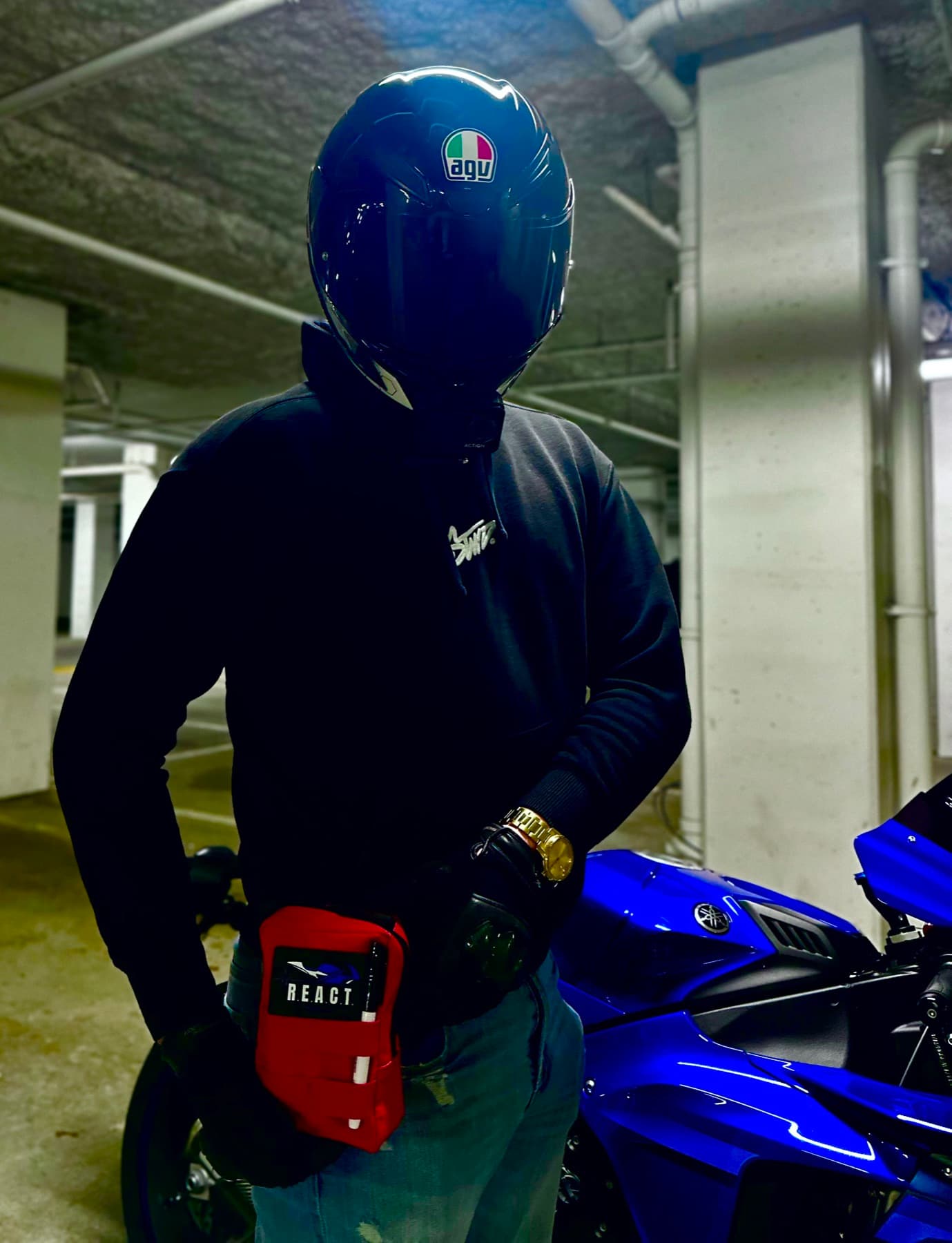 R.E.A.C.T. Kit worn by a rider next to a motorcycle
